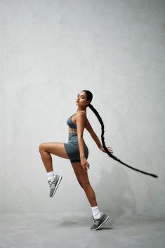 a woman with long hair holding a tennis racquet in her right hand while standing on one leg