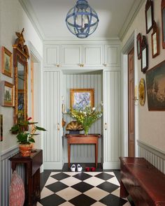 a hallway with checkered flooring and white walls, framed pictures on the wall