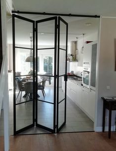 an open room divider in the middle of a kitchen with dining table and chairs