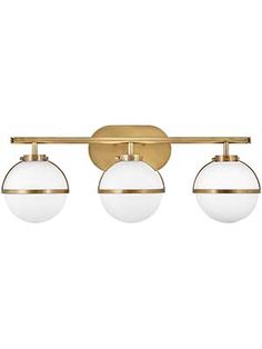 three light bathroom fixture in an antique brass finish with white glass globes on the sides