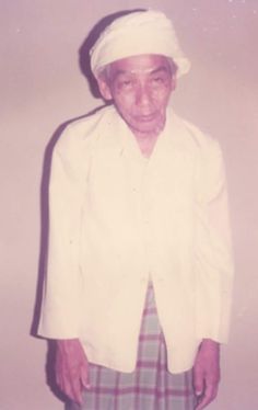 an old man in a white jacket and plaid skirt is posing for a photo with his hat on