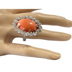 an orange and white ring sitting on top of a mannequin's hand