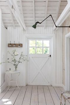 a room with white walls and wooden floors has a large barn door in the center