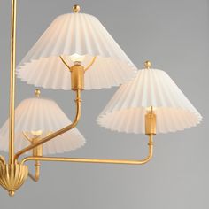 three light chandelier with white shades and gold trimmings on the arms