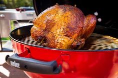 a roasting chicken is being cooked on the grill