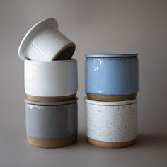 three ceramic cups stacked on top of each other, one with a lid and the other without