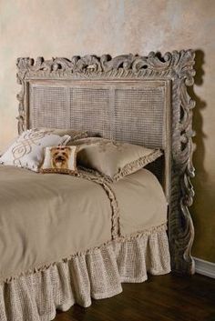 the bed is made up with ruffled linens and has an ornate headboard