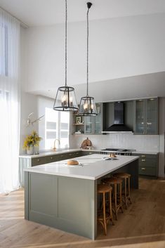 a large kitchen with an island in the middle and three stools at the end