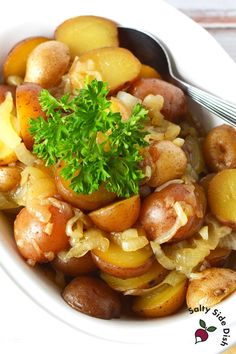 a white bowl filled with potatoes, onions and parsley on top of a wooden table