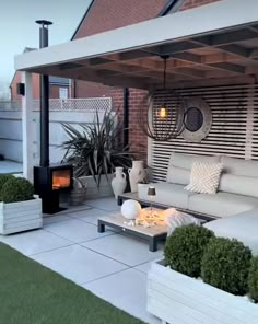 an outdoor living area with couches, tables and potted plants