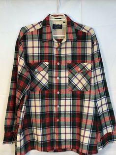 a red, green and white plaid shirt hanging on a clothes hanger in front of a white wall