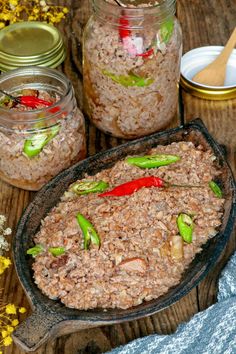 some food is sitting in a pan on a table next to jars and spoons