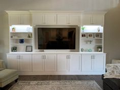 a living room with white cabinets and a flat screen tv on top of the entertainment center