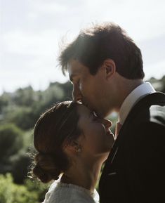 a man and woman standing next to each other in front of the sun on their wedding day