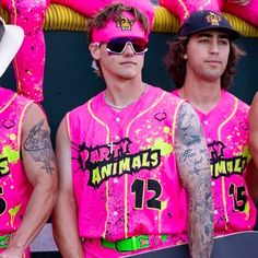 three men in pink shirts and hats are holding skateboards while wearing matching sunglasses with the same name on them