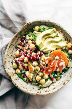 a salad with avocado, oranges and chickpeas in a bowl