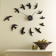 there is a clock with birds on it and fruit in the foreground, next to a fireplace