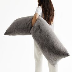 a woman is holding a large pillow in her hands