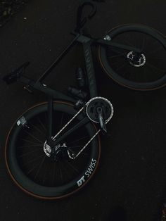 a black bike with orange spokes parked on the side of the road at night