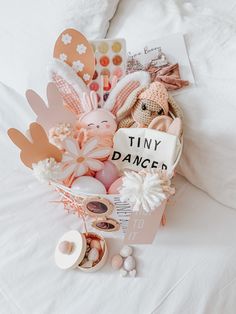 a basket filled with lots of different items on top of a white sheet covered bed