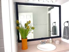 a bathroom sink with a mirror above it and flowers in a vase on the counter