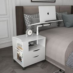 a bed with a laptop on top of it next to a night stand and nightstand