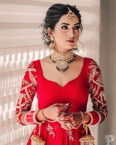 a woman in a red dress with jewelry on her neck and hands around her waist