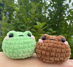 two small stuffed animals sitting on top of someone's hand in front of some trees