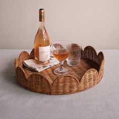 a wicker tray with two glasses and a bottle of wine sitting on top of it