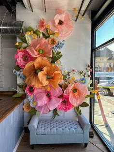 an arrangement of paper flowers decorates the wall in this office space, along with a bench and window