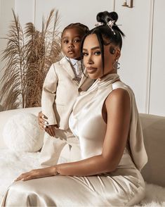 a woman sitting on top of a white couch holding a small child in her lap