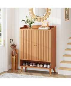 a wooden cabinet with shoes and umbrellas on it next to some stairs in a room