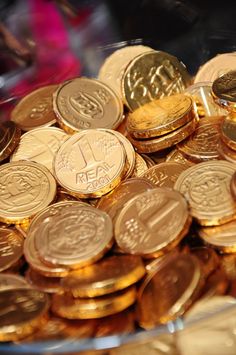 a pile of gold and silver coins sitting on top of each other in a bowl