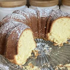 a bundt cake with one slice cut from it on a glass platter next to jars