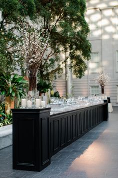 a long table with candles and vases on it in front of a large building