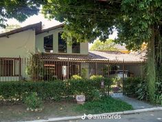 the house is surrounded by greenery and has an iron fence in front of it