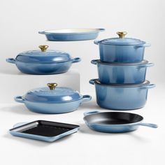 blue pots and pans with gold handles on white background, including one holding a casserole