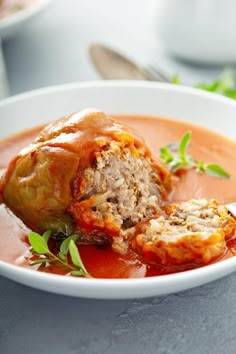 a white bowl filled with meatballs and tomato sauce on top of a gray table