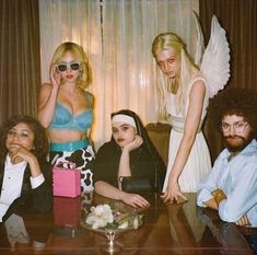 a group of people posing for a photo in front of a window with angel wings