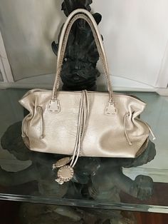 Beautiful bag in very good condition. Inside no stains outside some signs of wear on corners and on the bottom. It was very gently used. The color is a neutral pale gold beige. The original price was $450 and it is so worth it. Fabulous leather and a classic style. Im sorry to sell it but I have to part with some of my bags! I also have the same bag in orange in similar condition. I have included one photo if interested I with forward more. Please ask questions before purchase as there are no re Pre-owned Leather Bags For Daily Use, Pre-owned Leather Bag With Double Handle, Designer Gold Satchel Shoulder Bag, Pre-owned Leather Bags, Designer Gold Shoulder Bag For Daily Use, Designer Gold Shoulder Bag With Handles, Designer Gold Bag With Handle Drop, Pre-owned Leather Shoulder Bag For Everyday Use, Pre-owned Leather Tote Bag