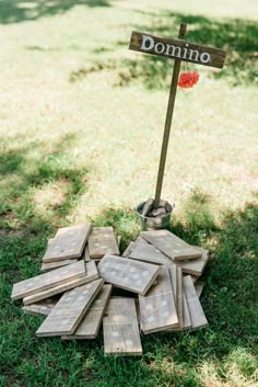 a pile of wood sitting in the grass next to a sign that says domino