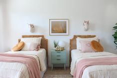 two twin beds in a bedroom with pink and white bedding, one has an animal head on the wall