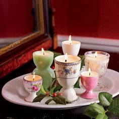 a white plate topped with lots of candles on top of a table next to a mirror