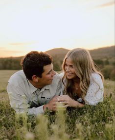 a man and woman are laying in the grass with their heads close to each other