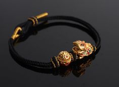 A 24k Real Gold Bracelet with a traditional Chinese lion-dance and treasure bowl is carefully handmade to commemorate wealth, fortune, strength, and good luck.  The Lion-Dance charm is made of 24K 999 Pure Gold and is 14mm wide, 16mm long, and 10.5mm high. Meanwhile, the Treasure Bowl charm has a diameter of 11.3 mm and a height of 11.1 mm, making a total gold weight of approximately 1.7 g.  This minimalist style bracelet features a handmade hand braided bracelet cord that is adjustable to fit comfortably on any wrist. The bracelet is personalized and made to order, making it a unique gift or addition to any jewelry collection. This Fengshui bracelet is 24k gold and is not gold-plated nor gold-filled. It is also a Made to Order item, and a wide range of sizes are available for customers wo Black Bracelets For Festivals, Black Festive Bracelets For Festivals, Adjustable Yellow Gold Bangle For Festivals, Traditional Adjustable Gold Bracelet Gift, Traditional Adjustable Gold Bracelet As A Gift, Traditional Adjustable Gold Bracelet For Gift, Adjustable Temple Jewelry Bangle Bracelets, Adjustable Bangle Bracelets In Temple Style, Adjustable Temple Jewelry Bangle For Festivals