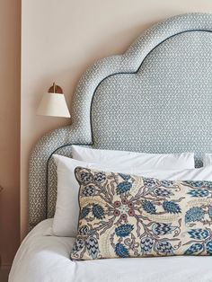 a white bed topped with a blue headboard next to a lamp