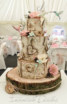 a three tiered wedding cake with flowers and birds on the top is decorated in white wood