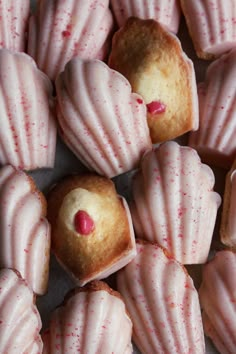 several pink cupcakes with white frosting and red sprinkles