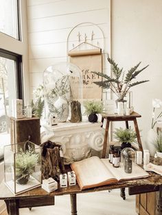 an open book sitting on top of a wooden table next to plants and other items