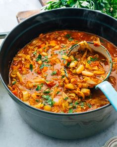 a pot filled with pasta and vegetables on top of a table next to other dishes